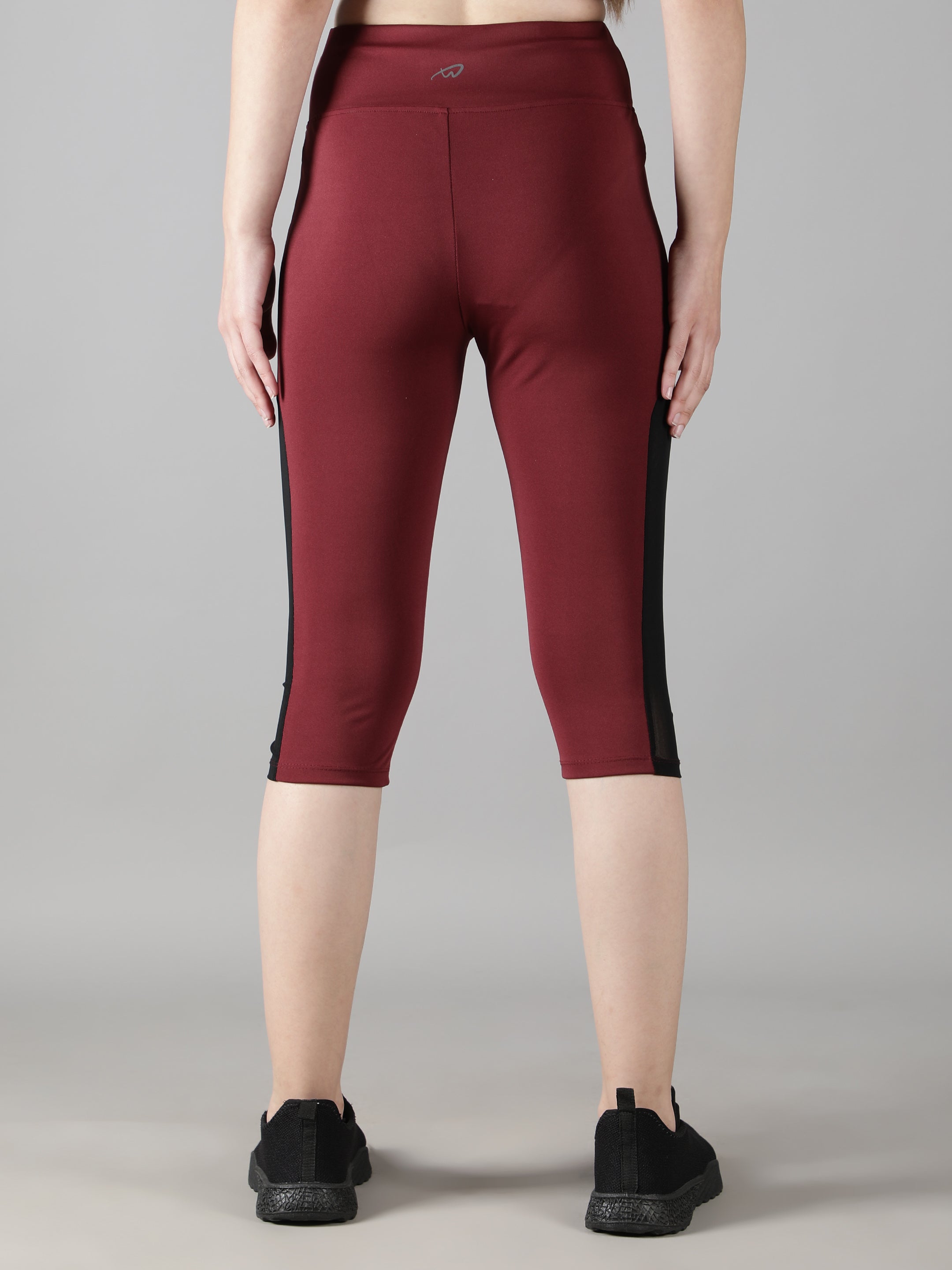 Close-up rear view focusing on the high waistband of Waylene's wine Capri tights, emphasizing the supportive fit.