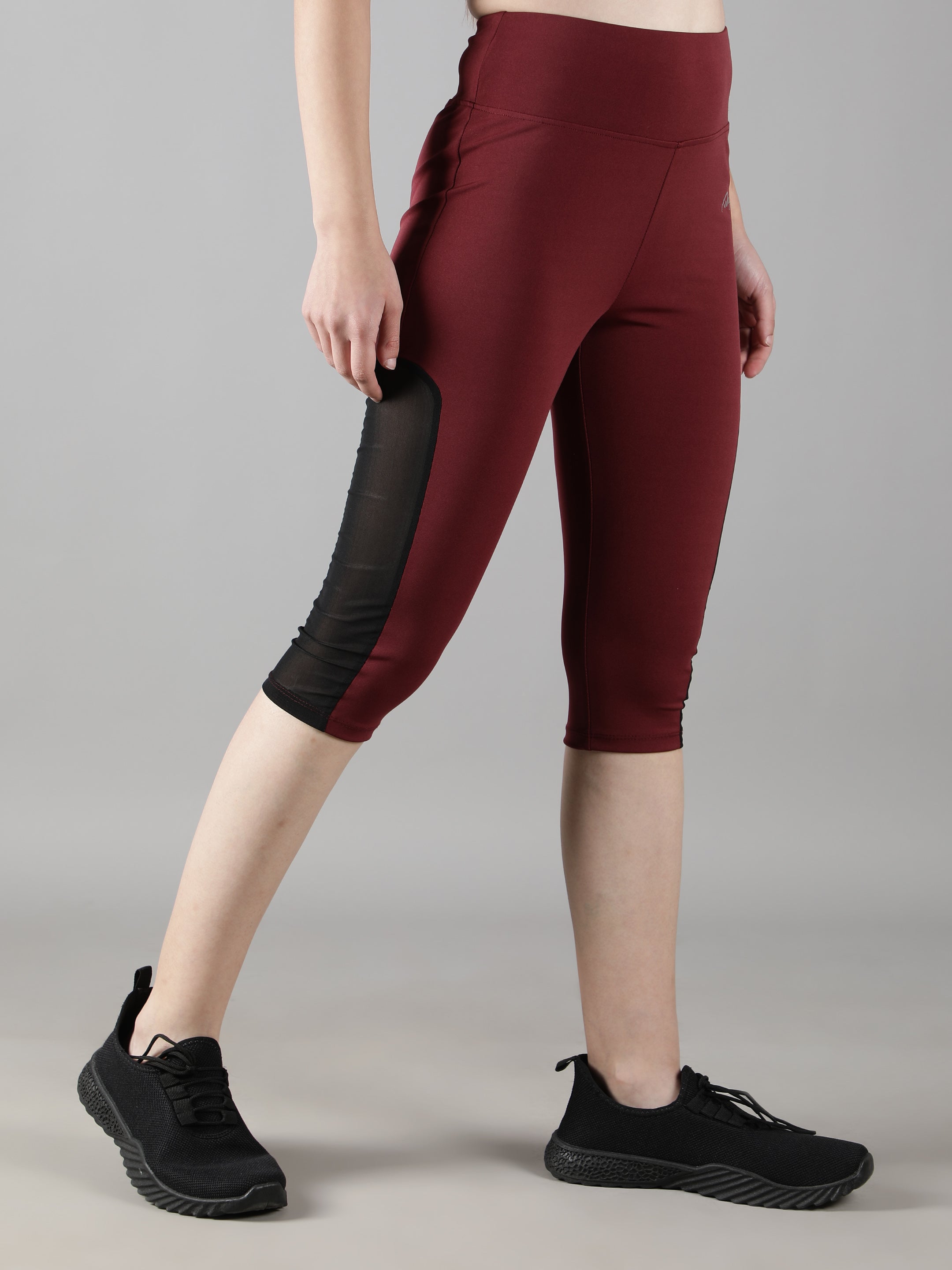 Model posing in Waylene's wine Capri tights featuring a mesh panel, illustrating the stylish and functional design.