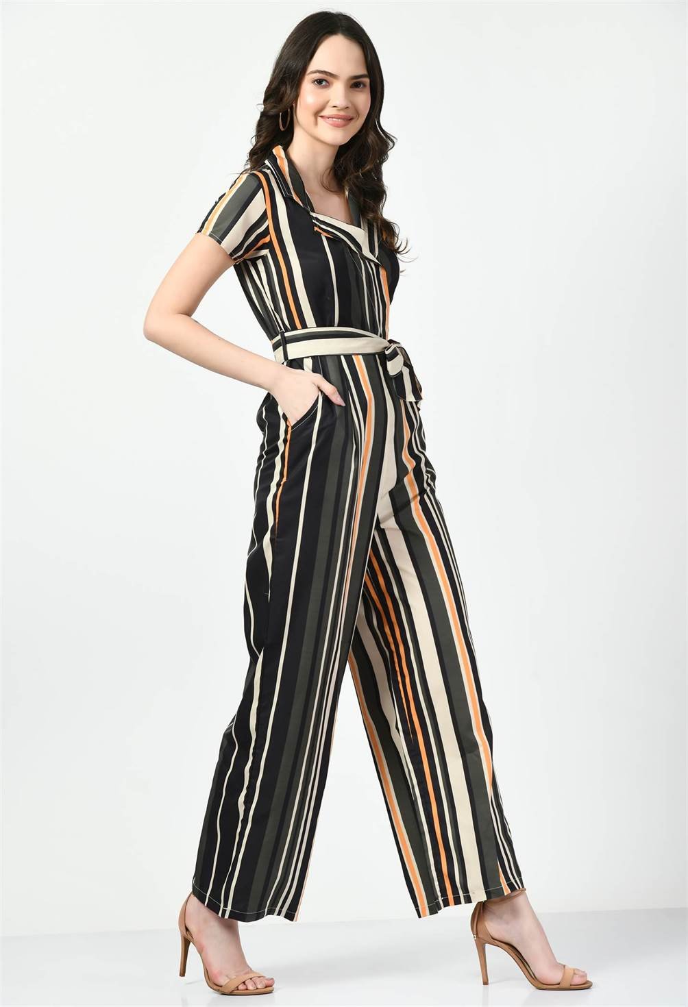 Waylene's elegant striped jumpsuit in multi-color with a collared neckline and tie waist. Model poses playfully with hands in pockets on a white background.